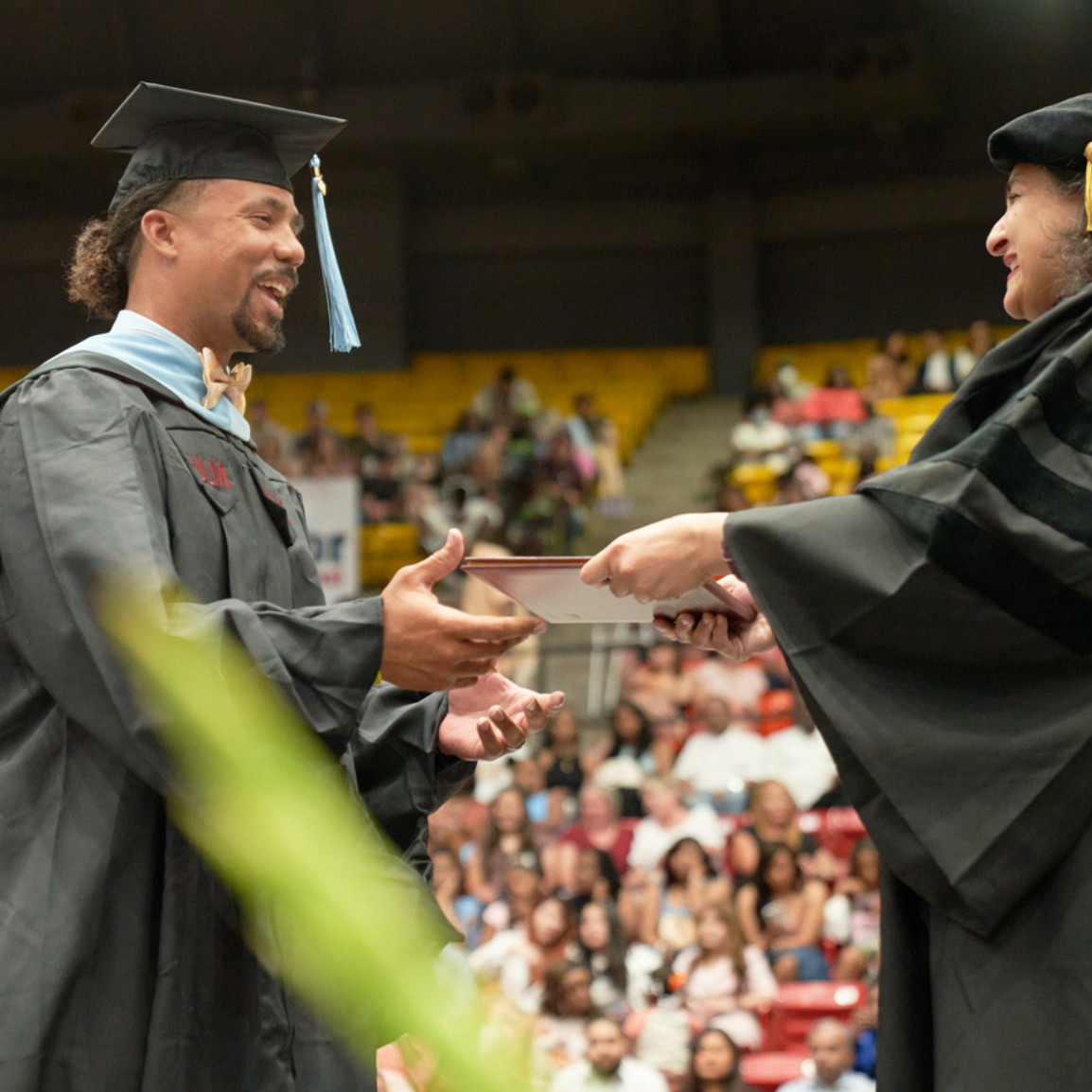 Student receiving Degree Graduate student receiving degree from dean, both are smiling